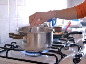 person stirring pot on gas stove